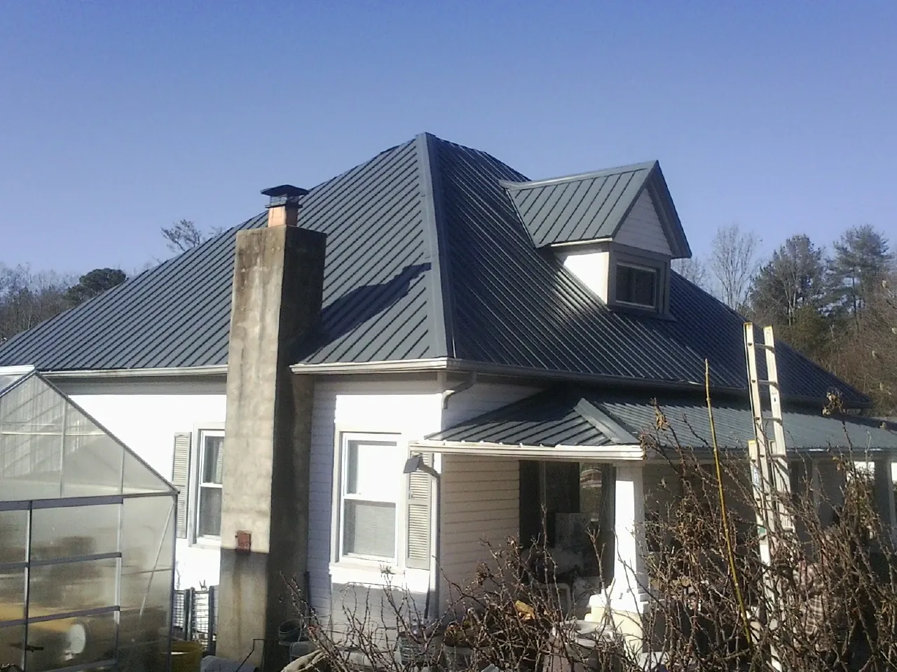 Dark blue standing seam metal roof on a white farmhouse with dormer — Slate & Tile Roof Repair by Roofing Brothers in Kokomo