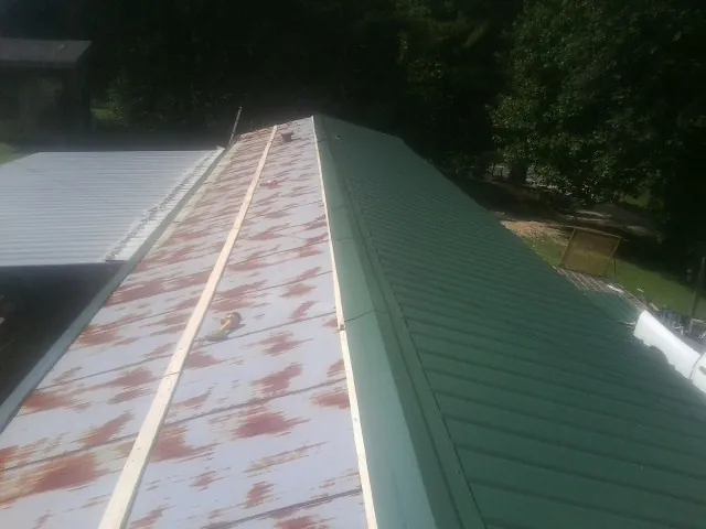 Old rusted panels beside newly installed green metal roofing — Wind Damage Roof Repair by Roofing Brothers in Kokomo
