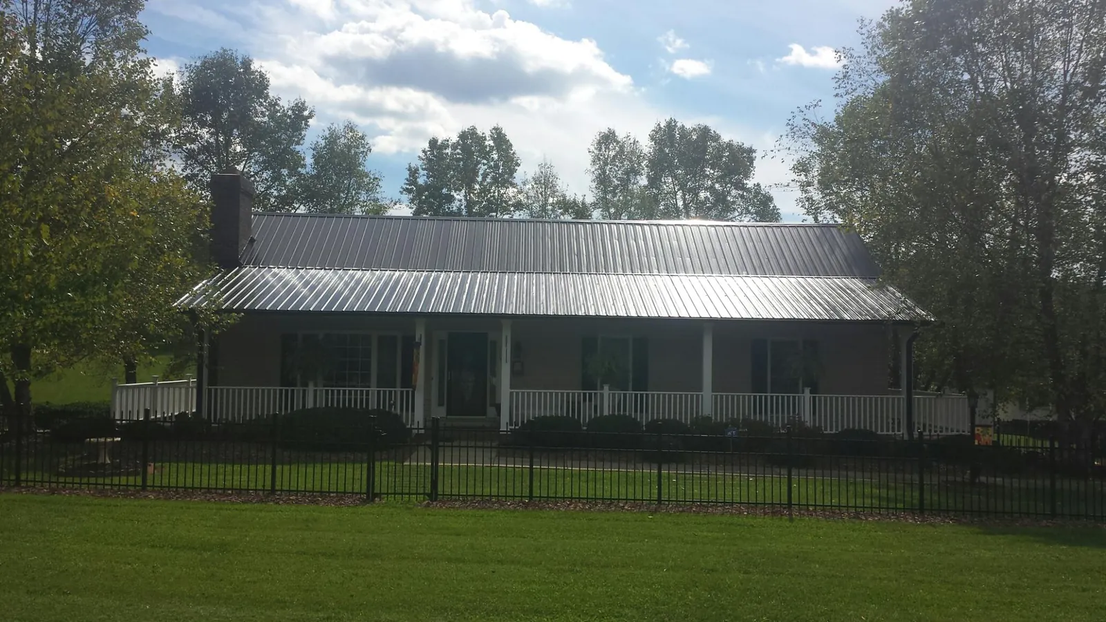 Gray metal roof on a brick ranch with a full width front porch — Gutter Guard Installation work by our crew in Kokomo
