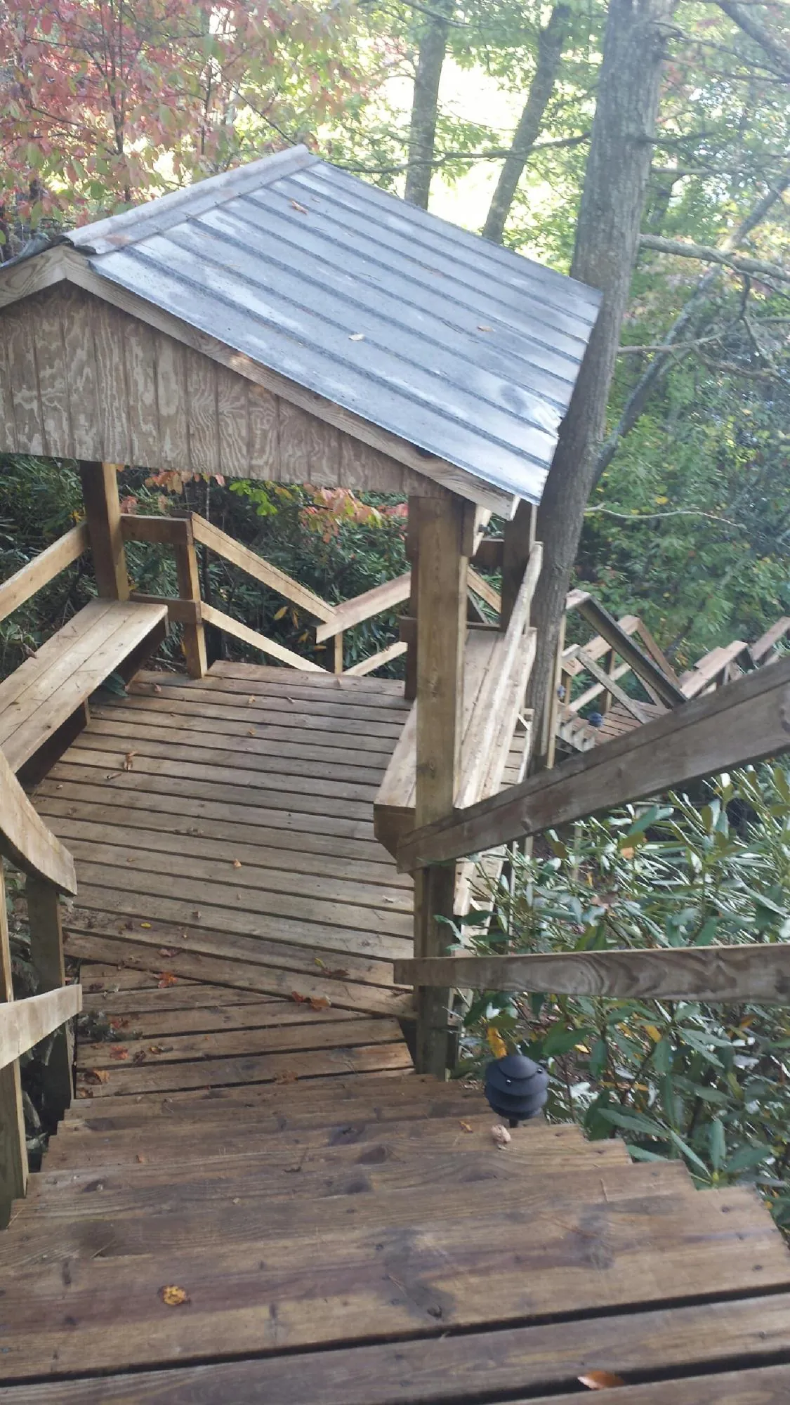 Metal roofed shelter over wooden steps on a wooded walkway — Skylight Repair & Installation work by our crew in Kokomo