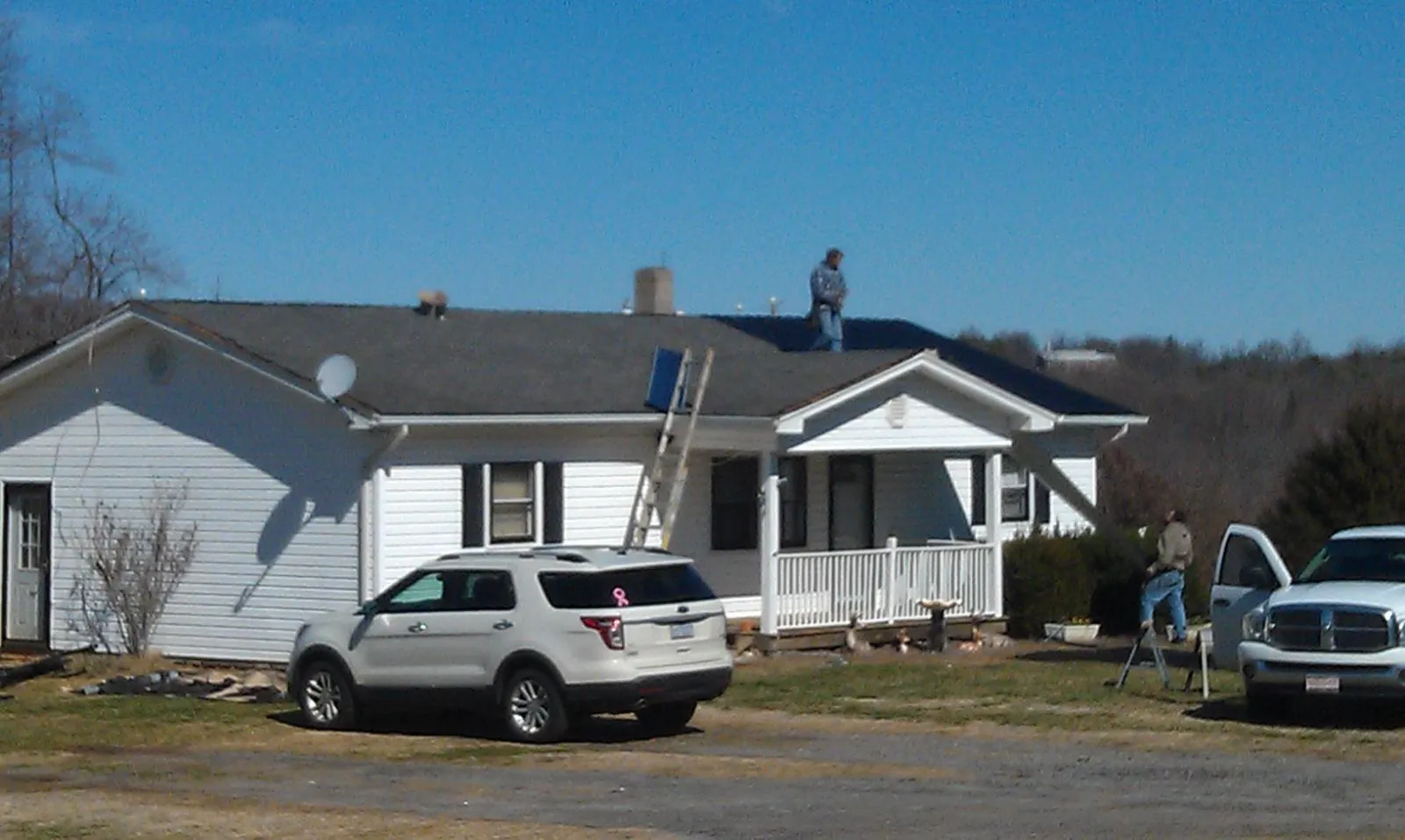 Roofers stripping shingles from a white ranch house roof in Kokomo