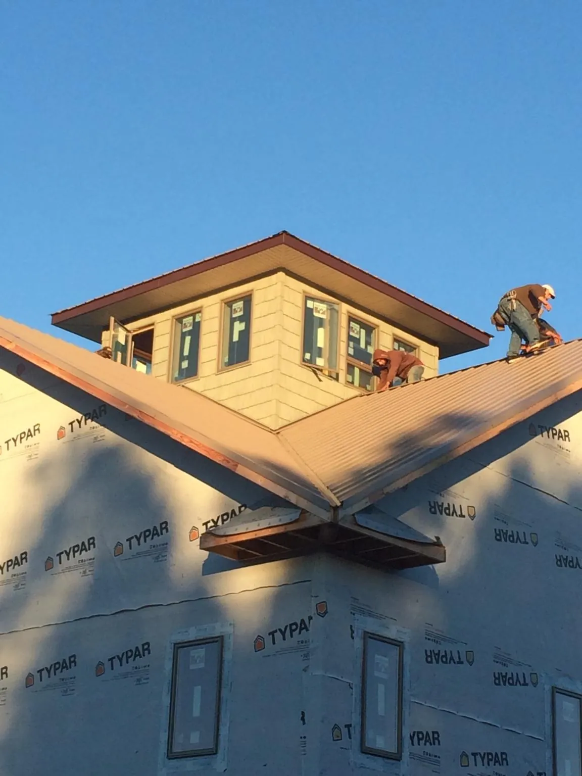Roofers working around a rooftop cupola on a new metal roof at sunset — Roof Waterproofing in Kokomo by Roofing Brothers